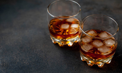 Two glasses with whiskey on a stone background with copy space for your text.