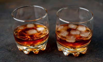 Two glasses with whiskey on a stone background with copy space for your text.