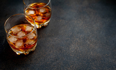 Two glasses with whiskey on a stone background with copy space for your text.