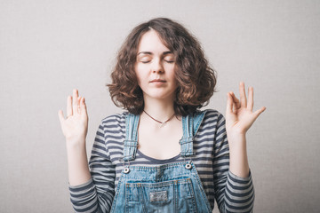 Woman meditating. On a gray background.