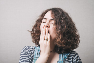 The woman yawns. On a gray background.