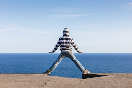 Boy looking out to sea with hands on the horizon