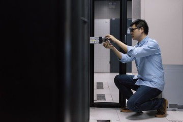 Server room technician inserting hard disk into server