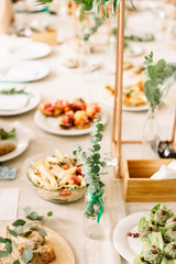 Festive table with different dishes and appetizers. Wedding table decor. Kinfolk lunch. 