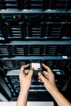 Server room technician inserting hard disk into server