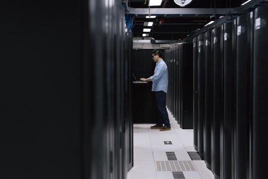 Server room technician using computer in server room