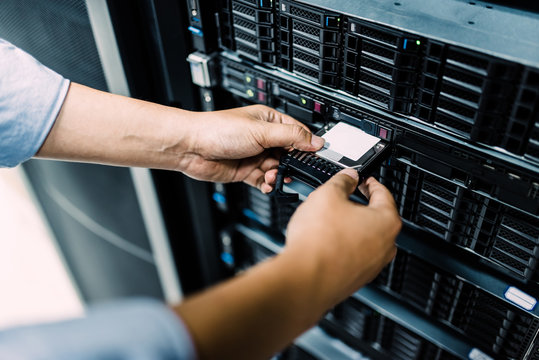 Server room technician inserting hard disk into server