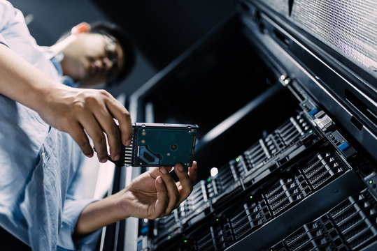 Server room technician inserting hard disk into server