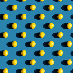 Repeating pattern of fresh lemons on blue background with natural sunlight and  hard shadow
