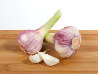 Close up of garlic bulb and cloves on wooden cutting board