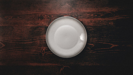 abstract dark grunge wooden table background with plate and silverware with space for text