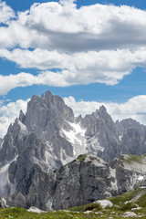 Iconic Italian mountainscape with a green meadow in the foreground and distant rocky peaks in the...