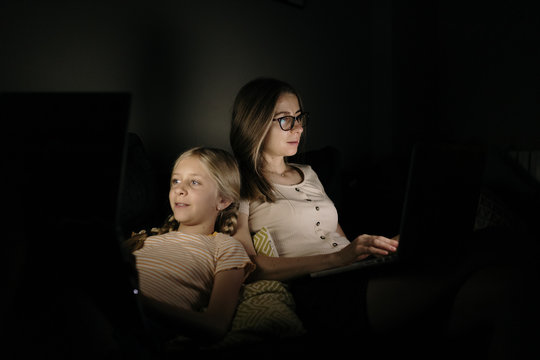 Mother and Daughter working with laptop at night at home.