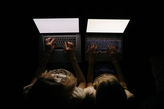 Mother and Daughter working at night with laptops photographed from above.