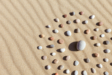 Fototapeta na wymiar pattern of colored pebbles in the shape of a circle on clean sand