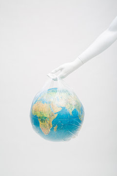 white mannequin's hand holding a globe in a plastic bag