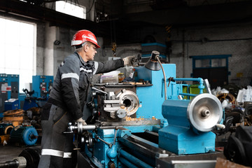 Worker taking tool from lathe