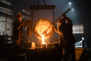 Men filling mold with liquid metal