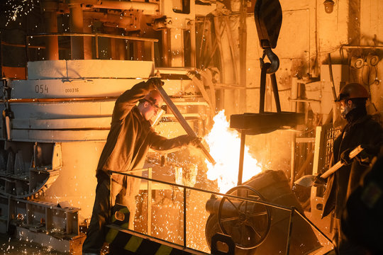 Men working with burning metal in foundry