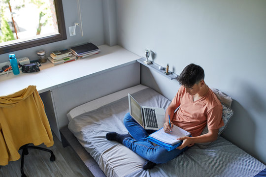 Teenager studying in his bed