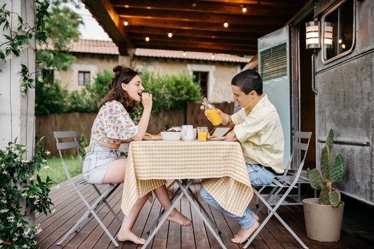 Young couple having breakfast near caravan