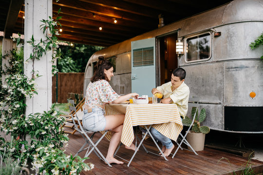 Young couple having breakfast near caravan
