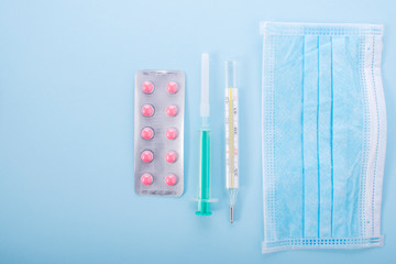 Coronavirus protection and treatment: medical mask, hand antiseptic, gloves, thermometer and pills. New coronavirus infection pandemic concept. Top view. Place for text