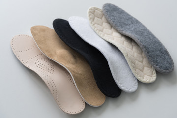 Studio photo of orthopedic insoles. A variety of orthopedic insoles are laid out in a row....