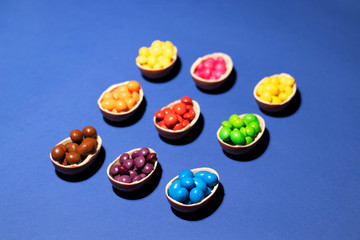 Set of chocolate eggs with colored jelly candies on a blue background. The photo was taken close for your bright and tasty design.