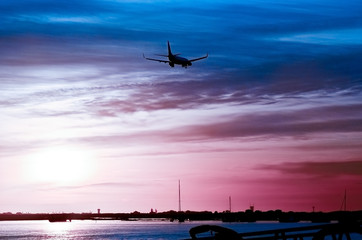 The plane flies to the airport over the river in the city of Faro in Portugal. silhouettes of...