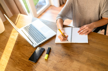 A young woman sits at a table with a laptop