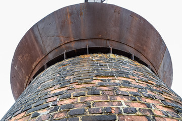 Rusty water tower against sky. Old water pump.