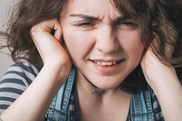 Young woman with  its hands covering his ears not to hear noise.