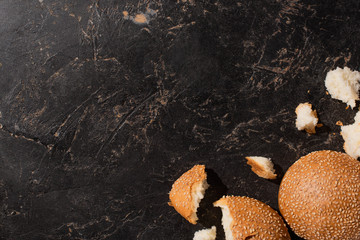 top view of torn sesame buns on stone black surface