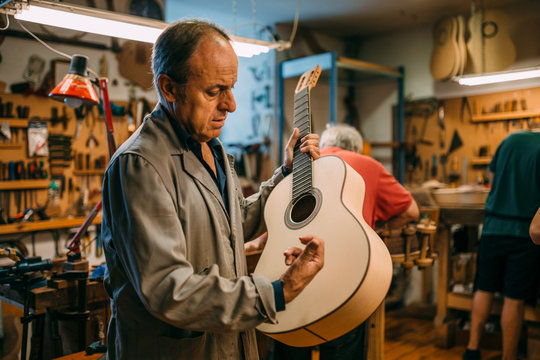 Senior luthier checking the sonority of a handcrafted spanish gu