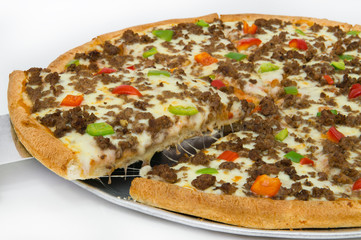 Meat pizza and lots of cheese, garnished with colored peppers. One piece is raised with a kitchen spatula from the dish.