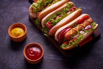 Hot dogs with sausage, fried onion, coriander leaves, cheese sauce and mustard, served on baking...