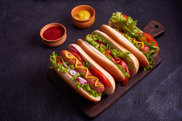 Hot dogs with sausage, fried onion, coriander leaves, cheese sauce and mustard, served on baking...