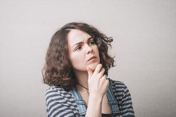 Girl thinking and holding his chin, wearing a jumpsuit