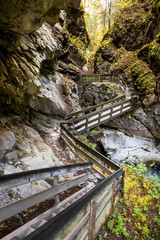 Wide angle view of a wooden catwalk making its way through a canyon in Italian alps