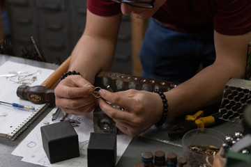 Crop jeweler examining ring