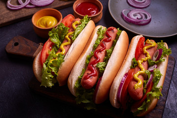 Hot dog with pickles and lettuce on blue concrete background.