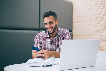 Optimistic guy communicating with friend on mobile in cafe