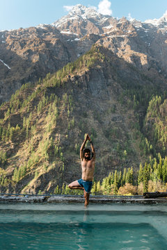 Shirtless man doing yoga in hot spring