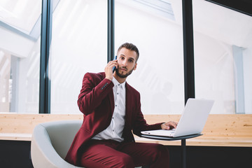 Fototapeta premium Confident entrepreneur talking on phone using laptop at workplace