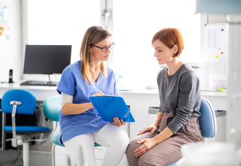 A dentist talking to woman in dentist surgery, a dental check-up.