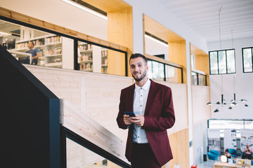 Cheerful businessman with smartphone standing on stairs
