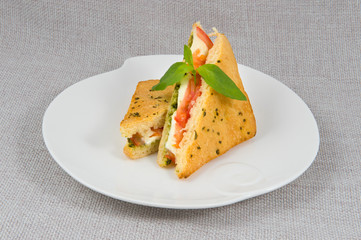 Casserole, cut into triangles with spinach, mozzarella, tomatoes on a white plate on a gray background
