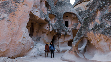 Travel couple walking around rock formations in Pasabag Valley, the valley of the monks in Cappadocia, Happy couple standing near cave houses surrounded by fairy chimneys at Pasabag Valley in Turkey © Seckin Ozturk