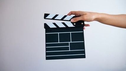 Female hand holding classic director empty film making clapperboard.